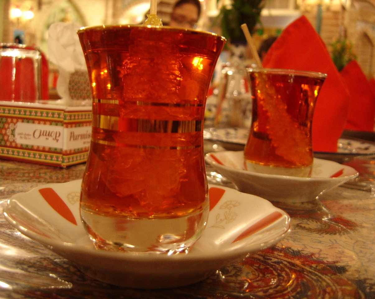 A tulip‑waisted estekan of black tea with a lump of nabāt rock sugar — the Iranian close to every meal.