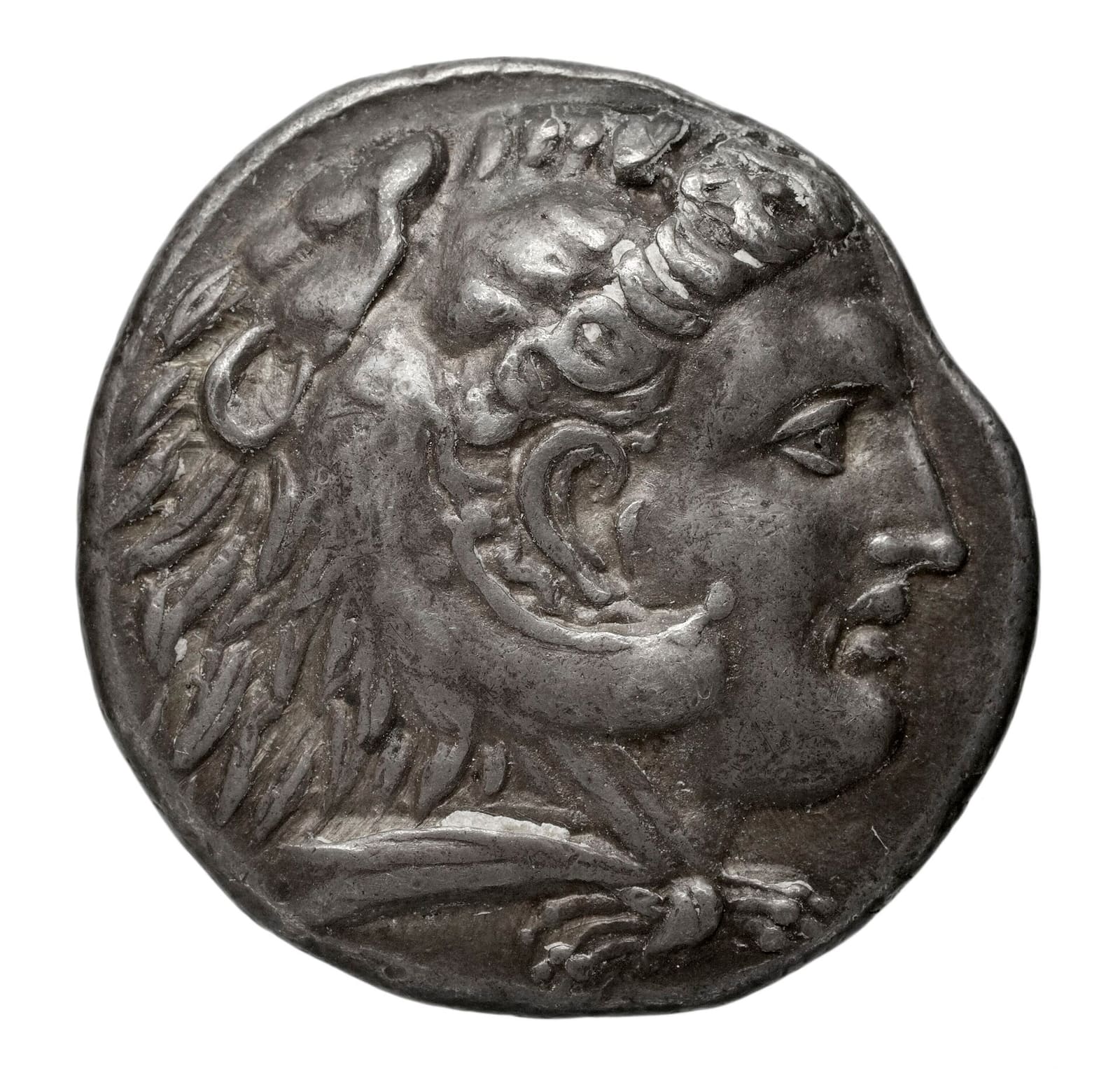A silver tetradrachm coin showing the head of Heracles wearing a lion scalp, minted under Alexander the Great.